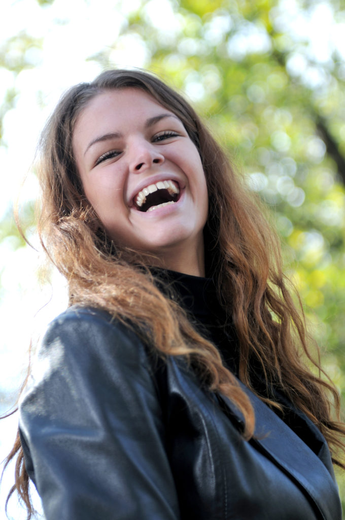 Laughing young woman with foliage in background